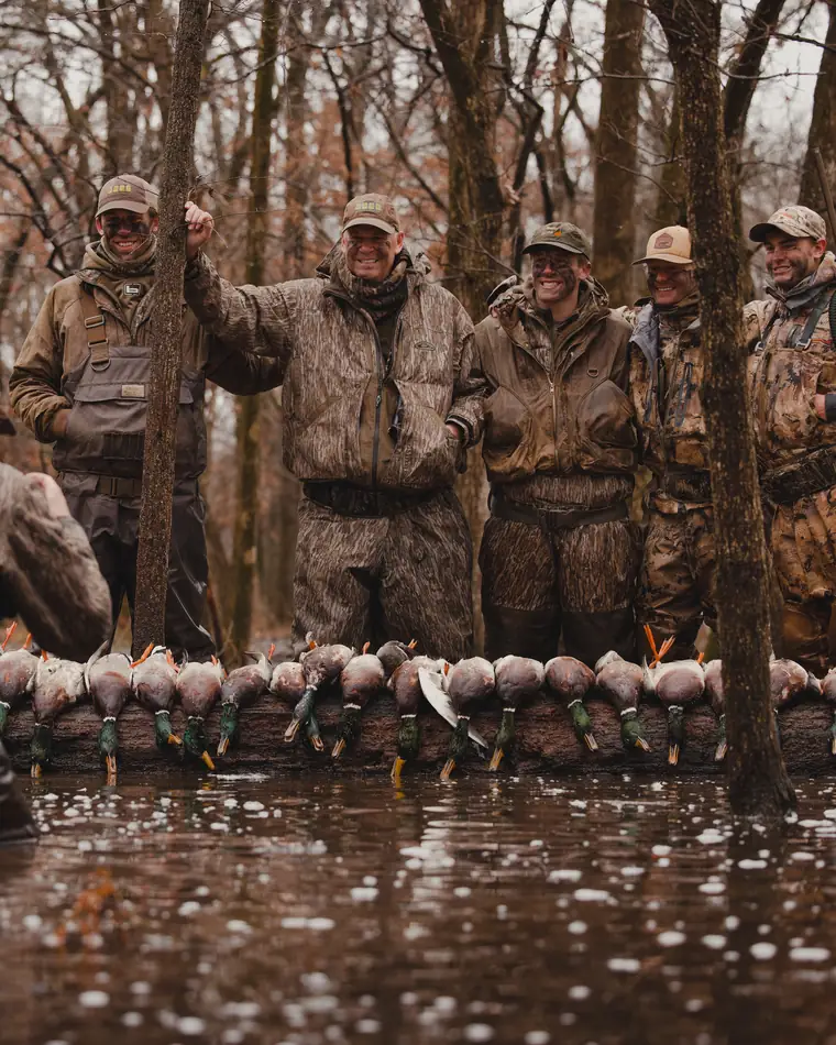 A group of hunters with a strap of ducks in flooded timber
